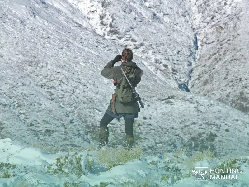 female hunter aiming rangefinder to uphill slope