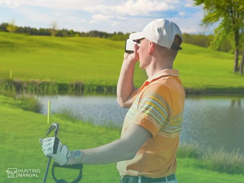golf player using rangefinder to measure field distance